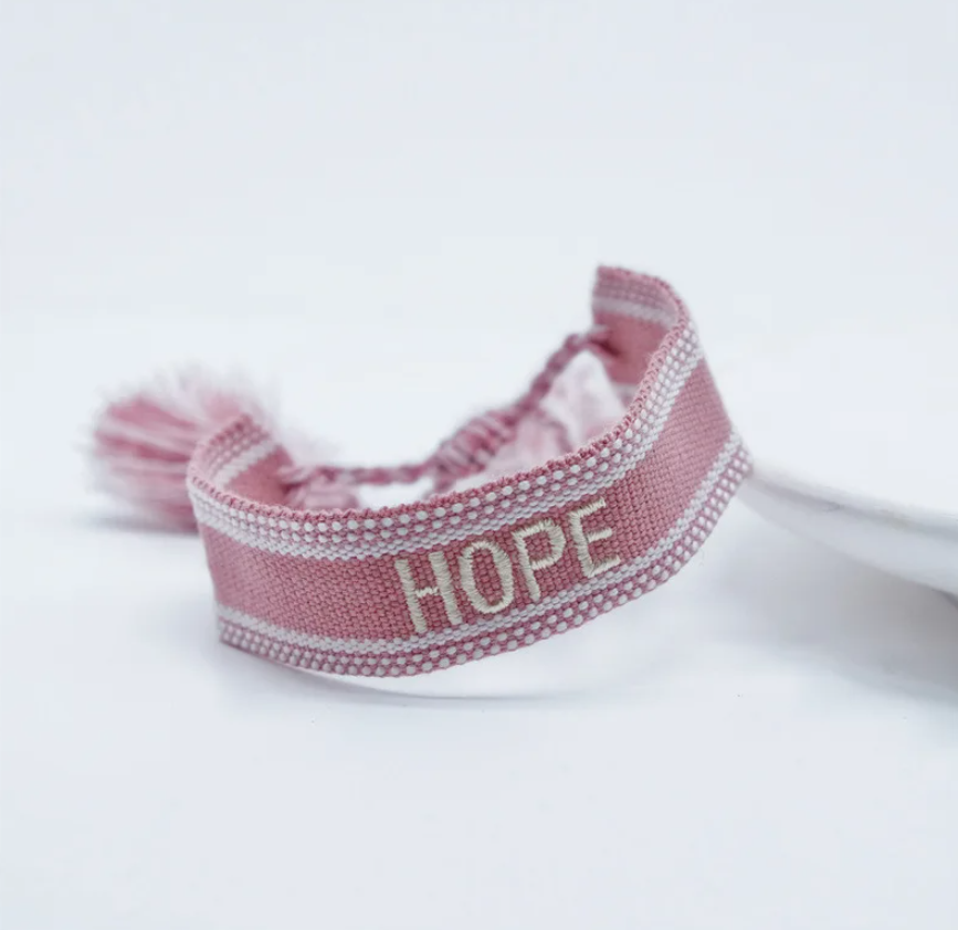 Bracciale in tessuto rosa con scritta "hope" ricamata bianca