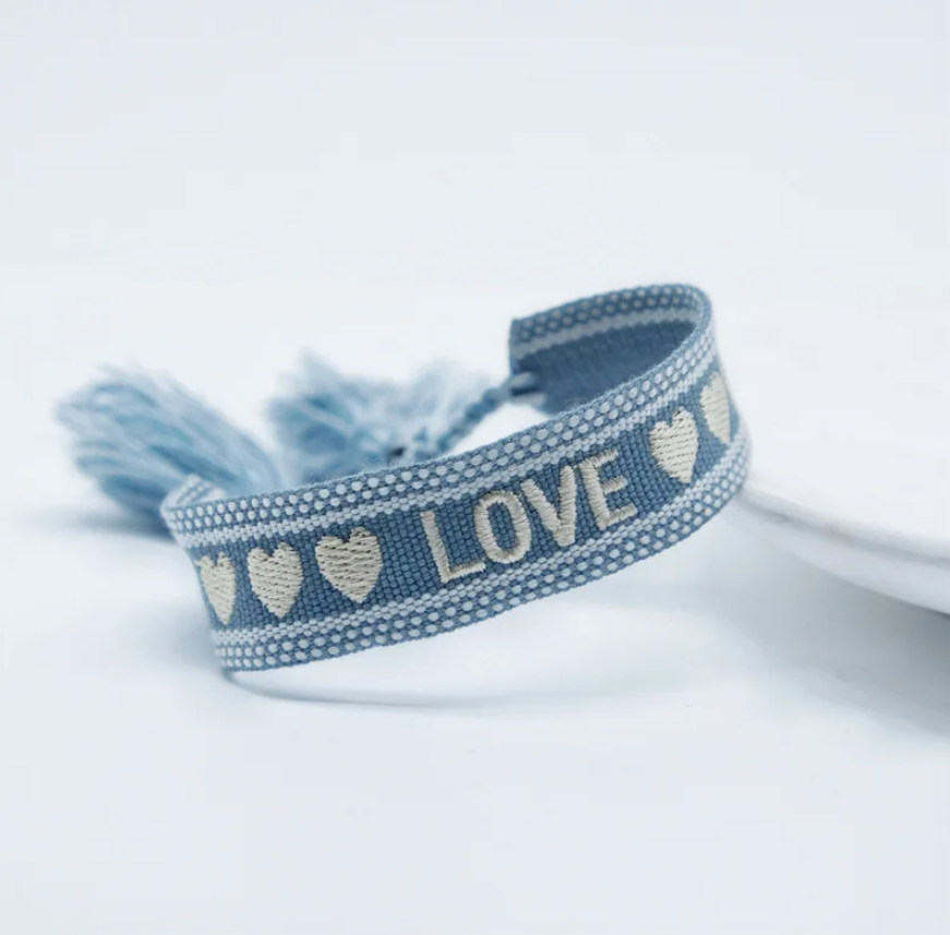 Bracciale in tessuto azzurro con scritta "love e cuoricini" ricamati bianchi